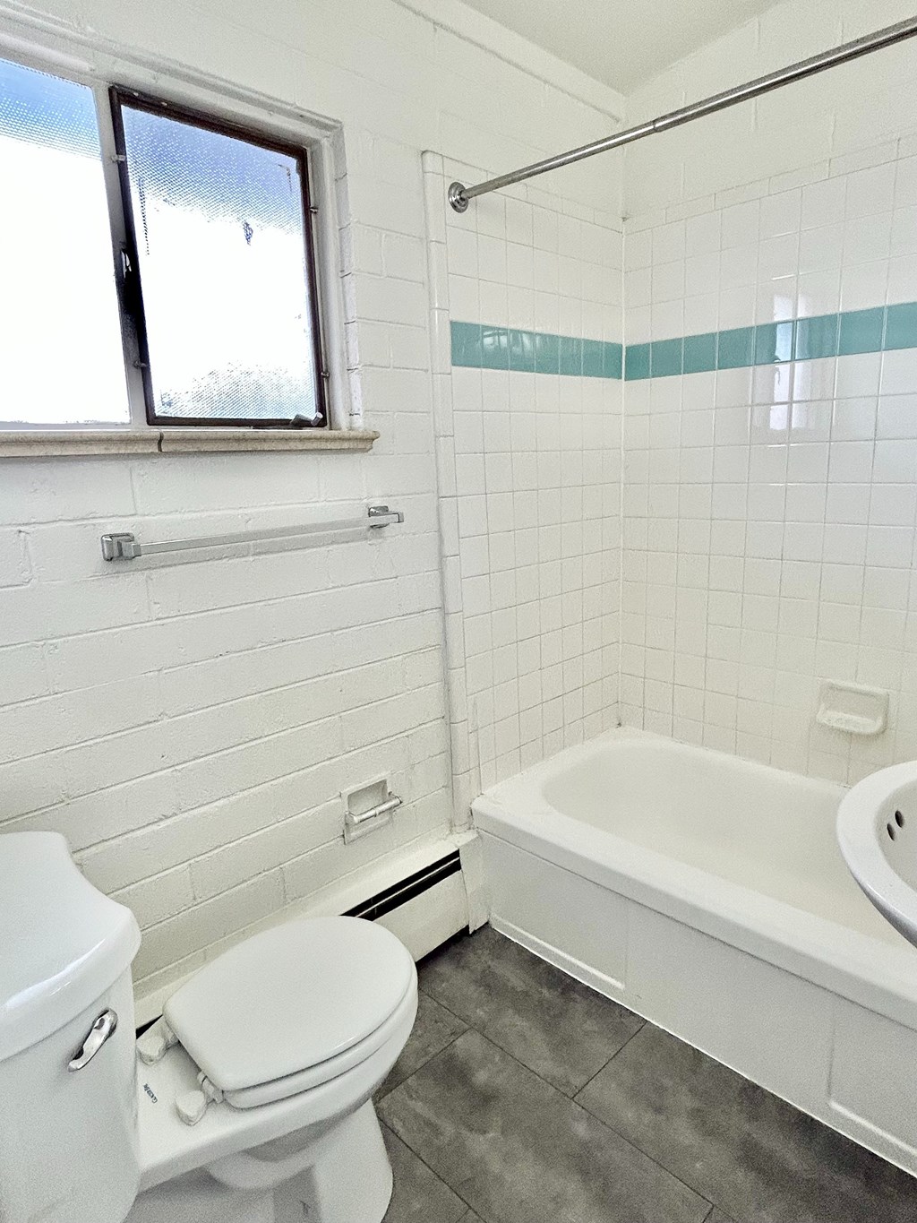 A white toilet sits next to a white bathtub in a bathroom.