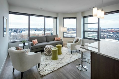 A living room with a grey couch, a white chair and a white sofa.