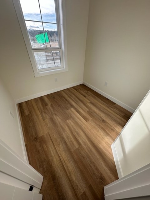 A room with wooden floors and a window overlooking a snowy landscape.