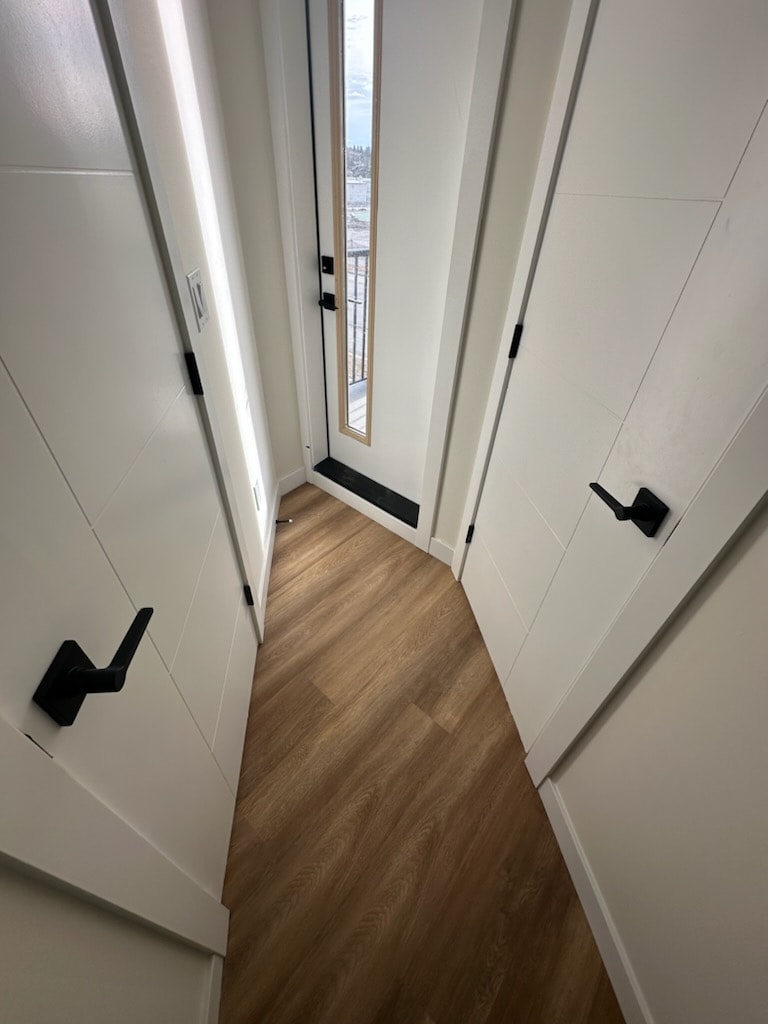 A hallway with a wooden floor and white walls.