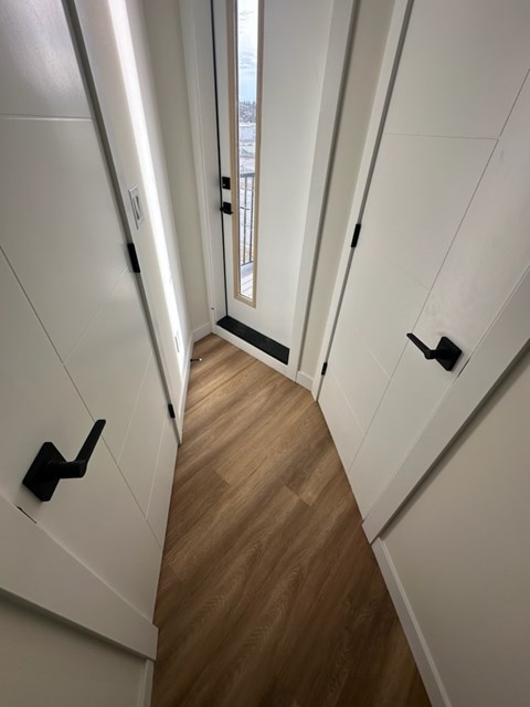 A hallway with a wooden floor and white walls.