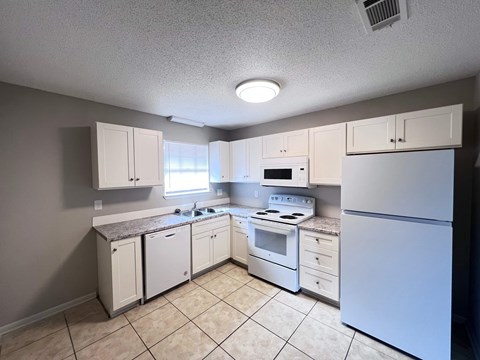 A kitchen with white appliances and cabinets.