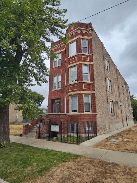 A tall red brick building with a black iron fence in front.