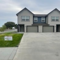 A house with a garage and a sign in front of it.
