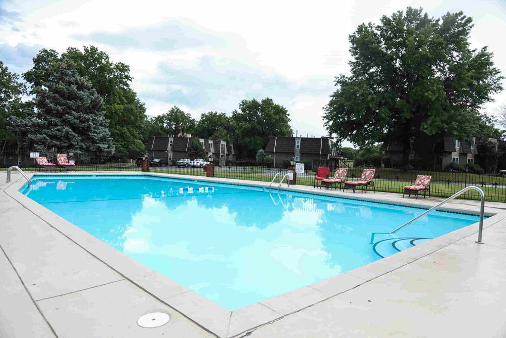 A large swimming pool with a few chairs around it.