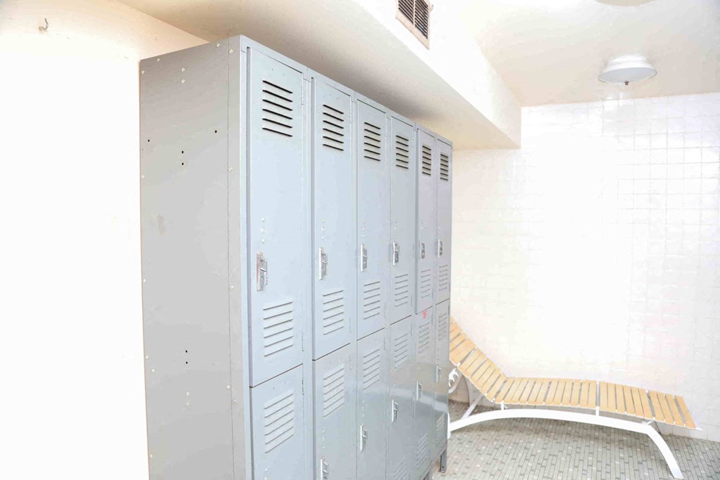 A row of white lockers in a room with a bench.