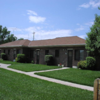 A building with a brown roof and a green lawn in front.