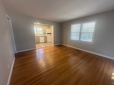 A room with wooden flooring and two windows.