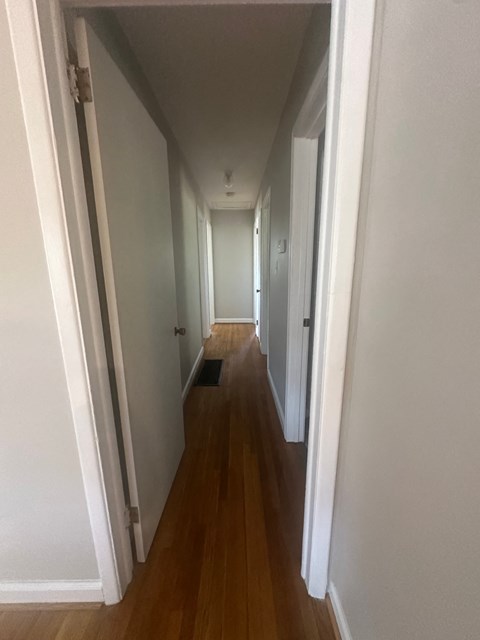 A long hallway with white walls and wood floors.
