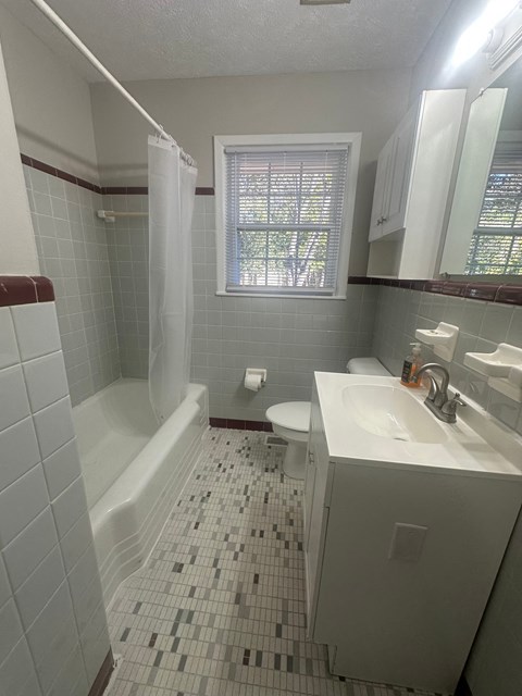 A white toilet is in a bathroom with a white sink and a white bathtub.