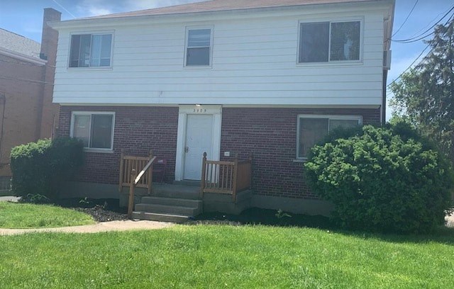 A house with a white siding and a red brick base with a white door and windows.