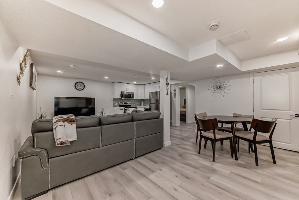 A modern living room with a grey sofa and a wooden dining table.