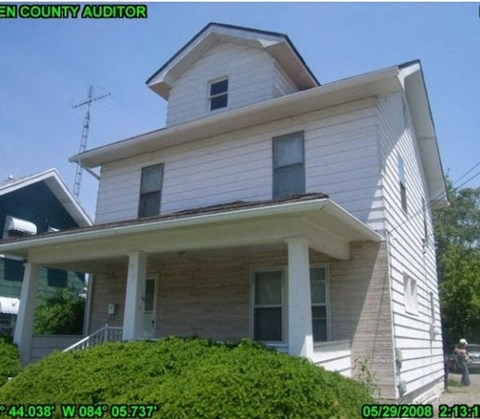 A white house with a black roof and a chimney.