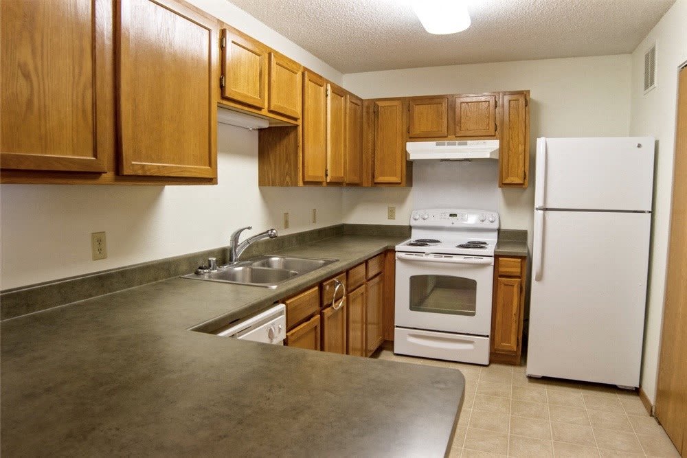 A kitchen with white appliances and wooden cabinets.