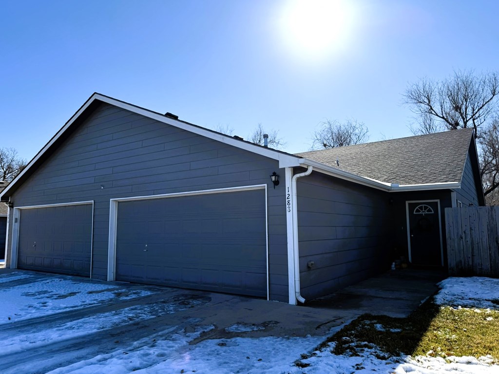 A house with a grey garage door and a black door.