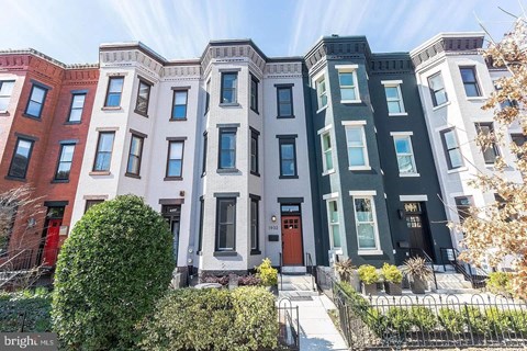 A row of townhouses with different colored front doors.