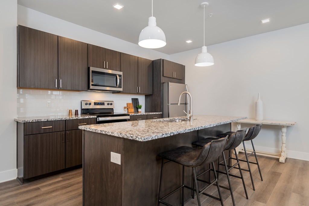 A kitchen with brown cabinets and a marble countertop.