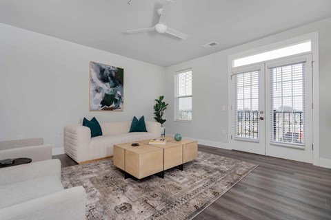 A living room with a white couch, a wooden coffee table, and a painting on the wall.