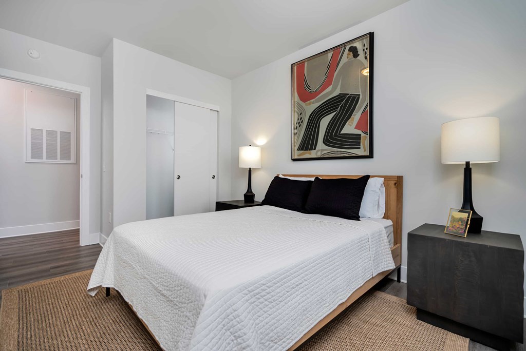 A bedroom with a large bed and a painting on the wall.
