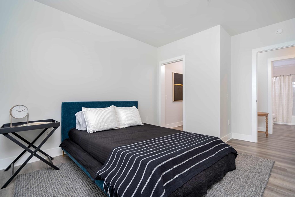 A bedroom with a bed, a clock, and a table.