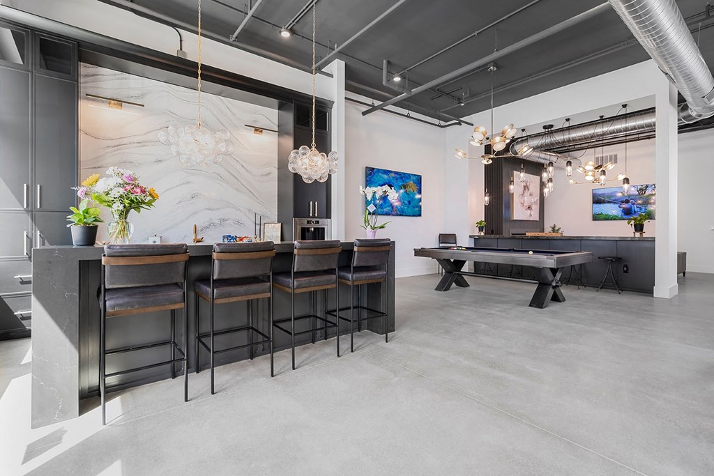 A modern bar area with a long counter and stools.