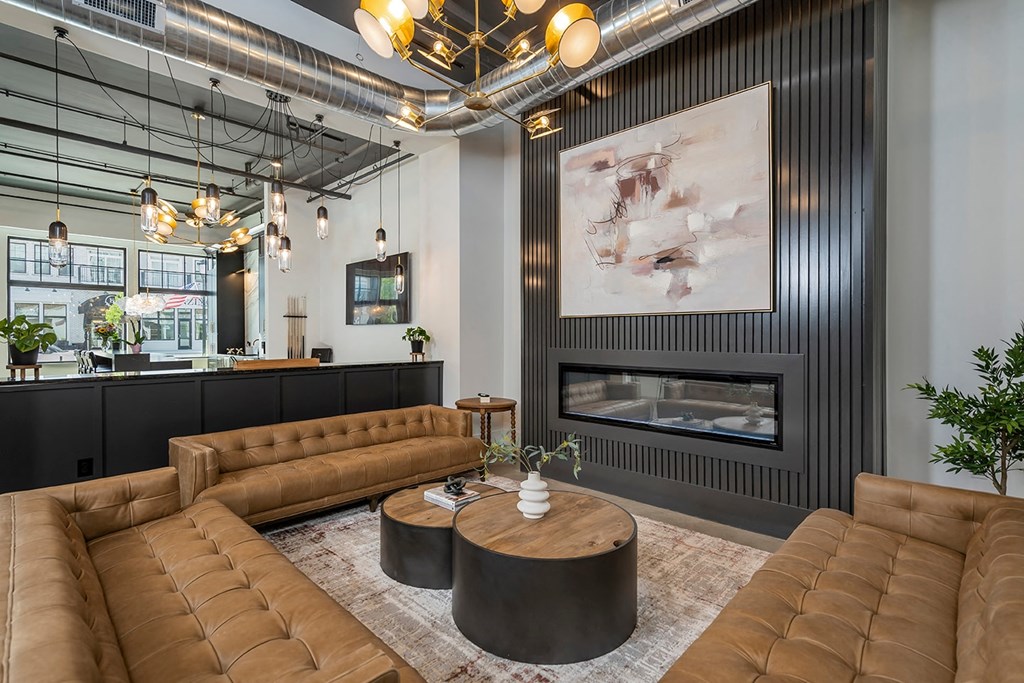 A modern living room with a fireplace and brown leather furniture.