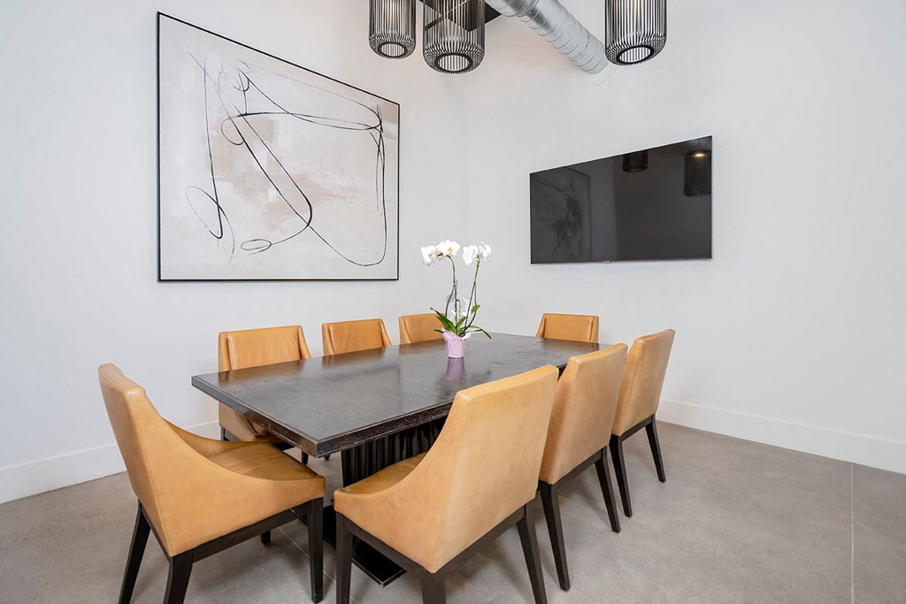 A dining table with chairs and a painting on the wall.