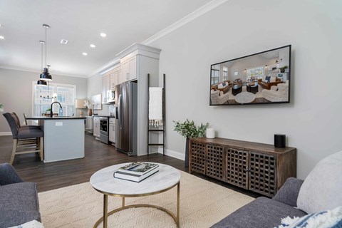 A modern living room with a coffee table, a grey sofa, and a large painting on the wall.