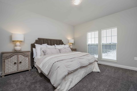 A bedroom with a large bed and a nightstand with a lamp.