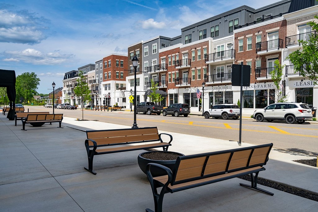 A row of benches are lined up on a sidewalk.