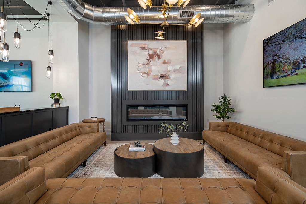 A modern living room with a fireplace and brown leather couches.