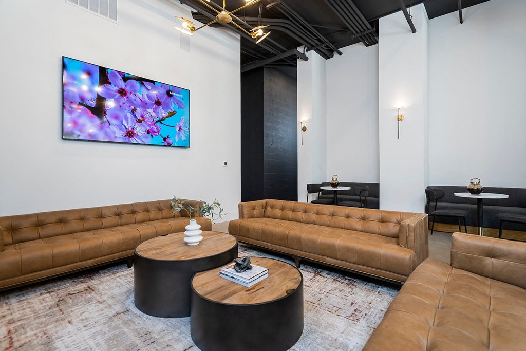 A living room with brown leather couches and a large painting on the wall.
