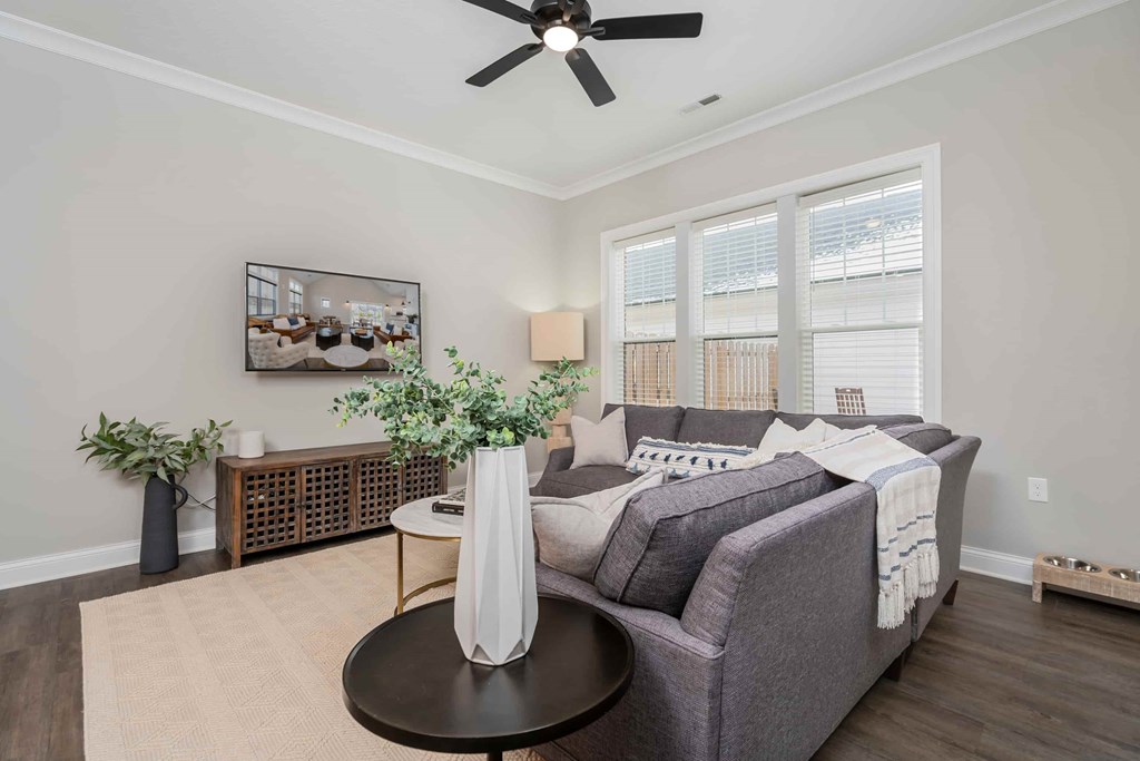 A living room with a grey couch, a coffee table, and a ceiling fan.