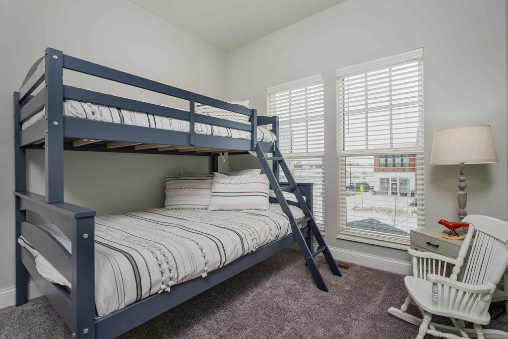 A bedroom with a bunk bed and a chair.