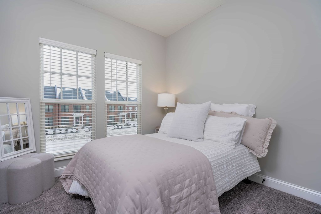 A bedroom with a large bed and a window overlooking a cityscape.