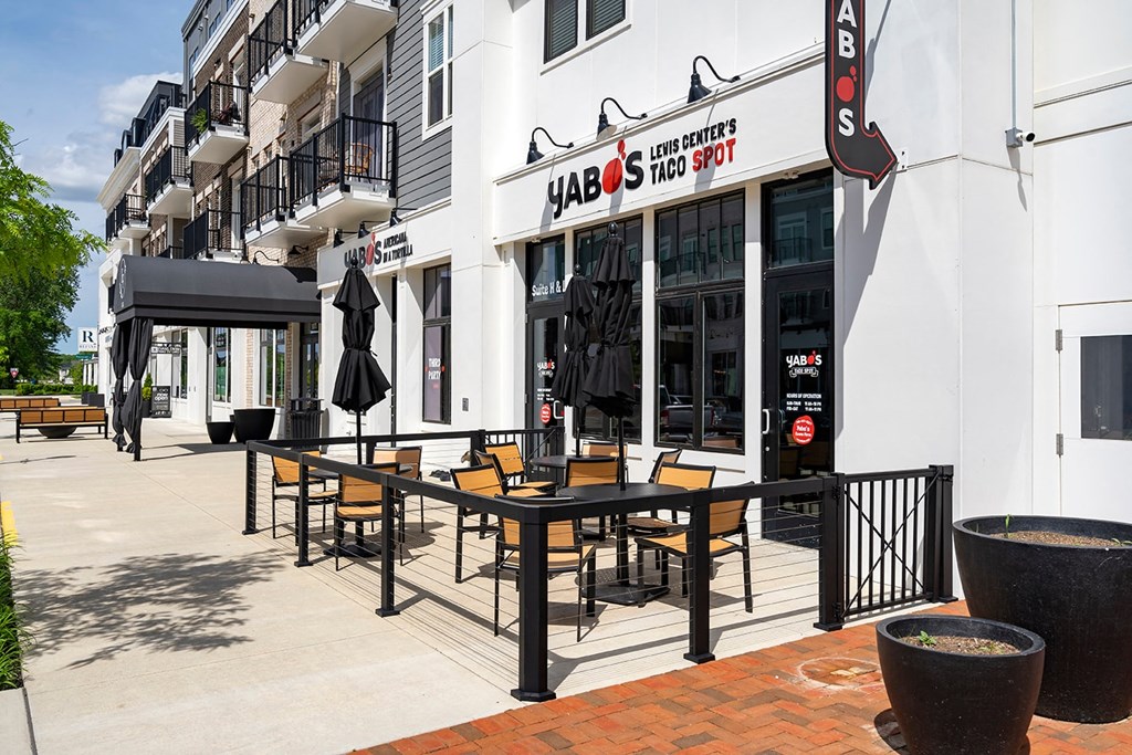 A restaurant named HABOS Taco Spot is located in a white building with black railings and a black awning.