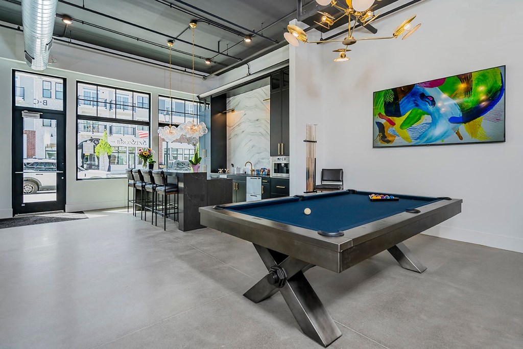 A pool table is in the middle of a room with a painting on the wall.