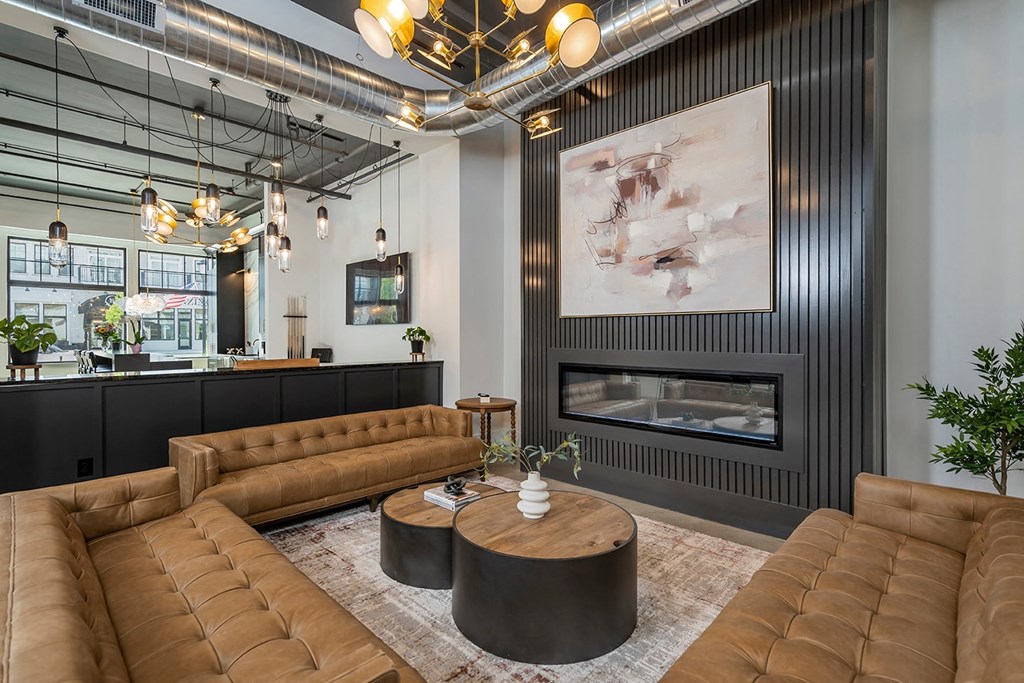 A modern living room with a fireplace and brown leather furniture.