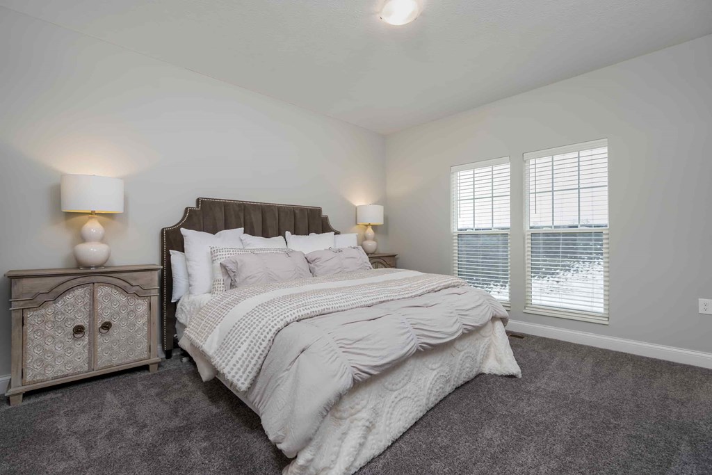 A bedroom with a large bed and a nightstand with a lamp.