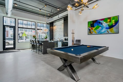 A pool table is in the middle of a room with a painting on the wall.