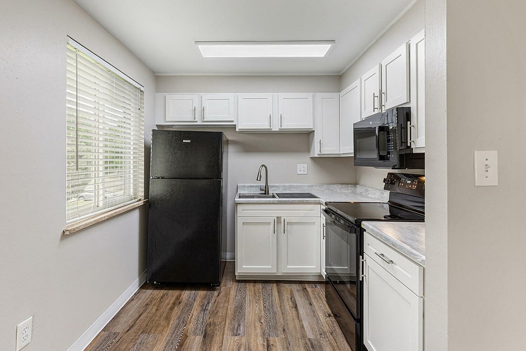 A kitchen with black appliances and white cabinets.
