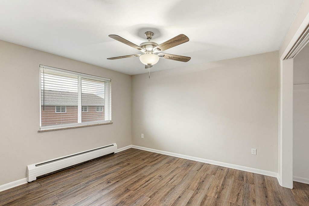 A room with a ceiling fan and wooden flooring.