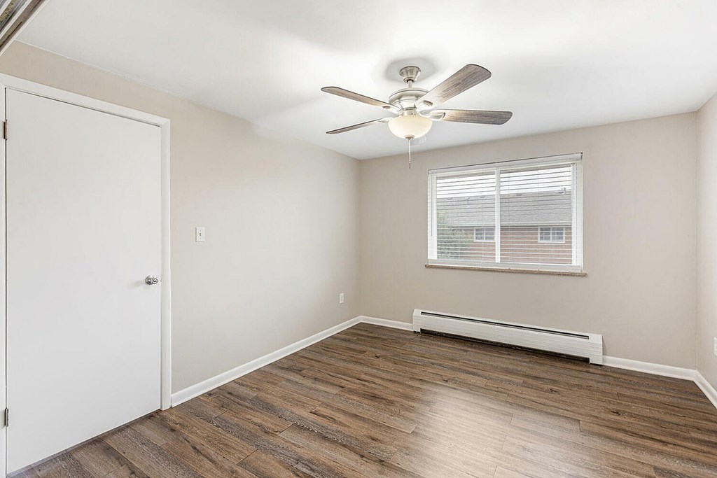 A room with a ceiling fan and a window with blinds.