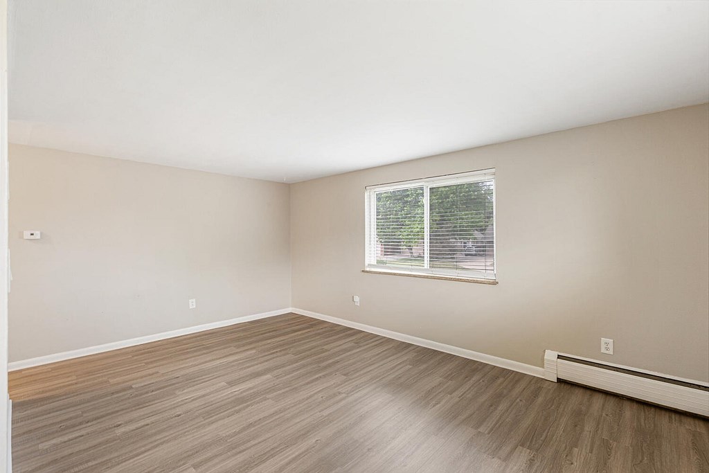 Empty room with a window and wooden flooring.