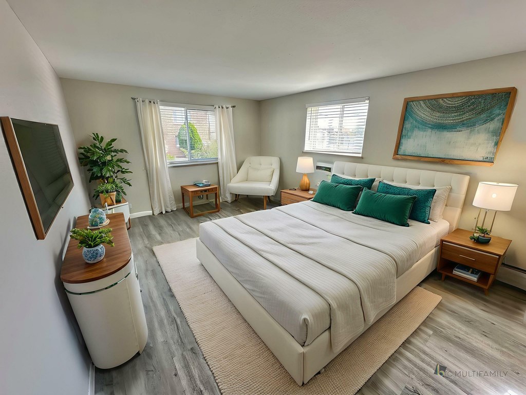 A black fridge in a kitchen with wooden floors and a window.