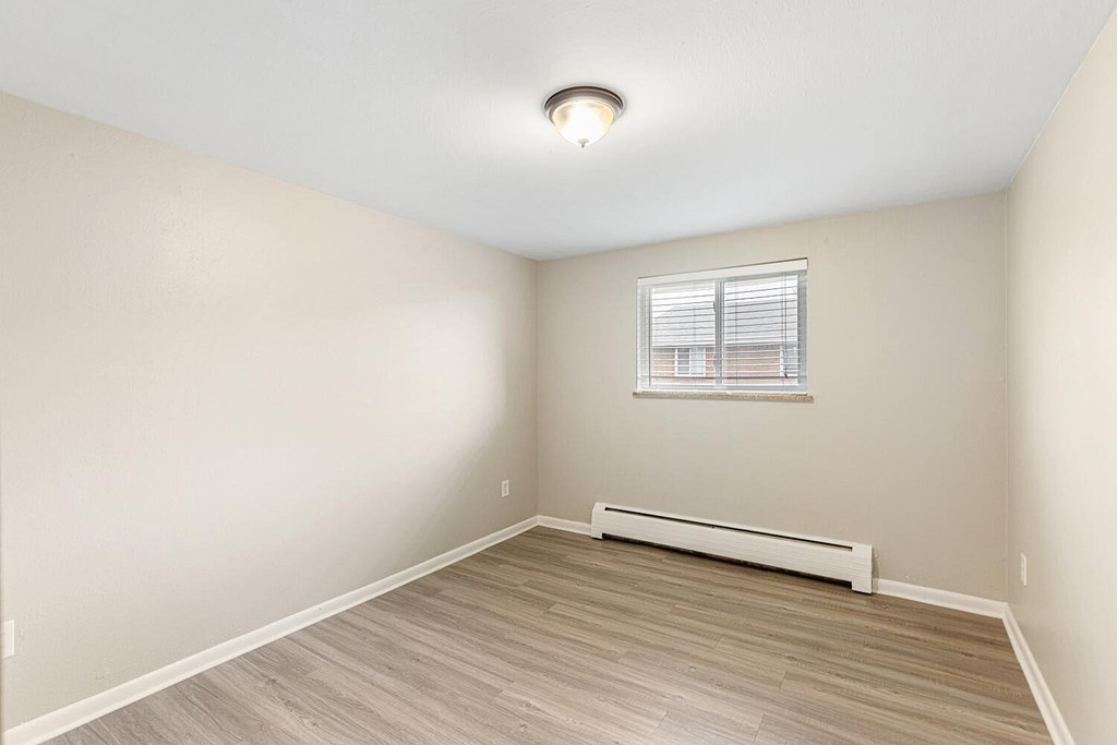 A room with a window and a radiator on the floor.