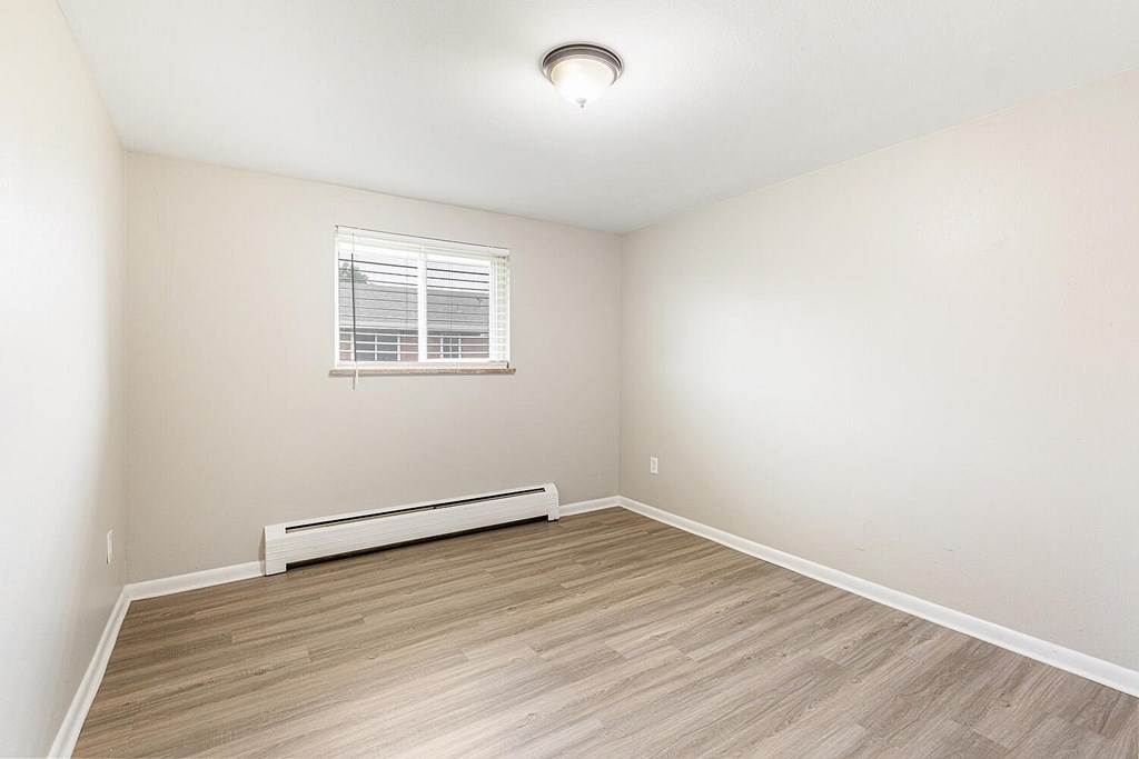 A room with a window and a radiator on the floor.