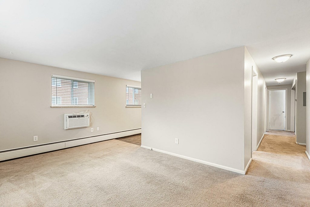 A spacious room with beige carpeting and white walls.