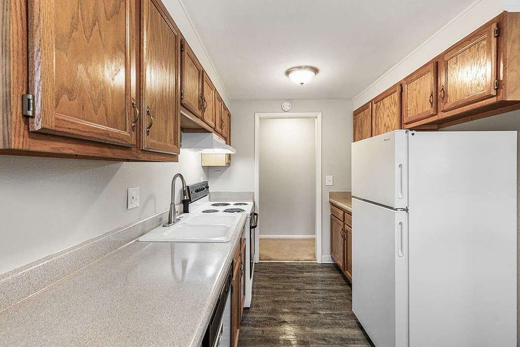 A kitchen with a white fridge and wooden cabinets.