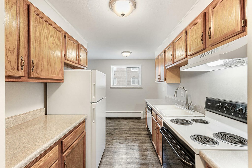 A kitchen with wooden cabinets and a white stove top oven.